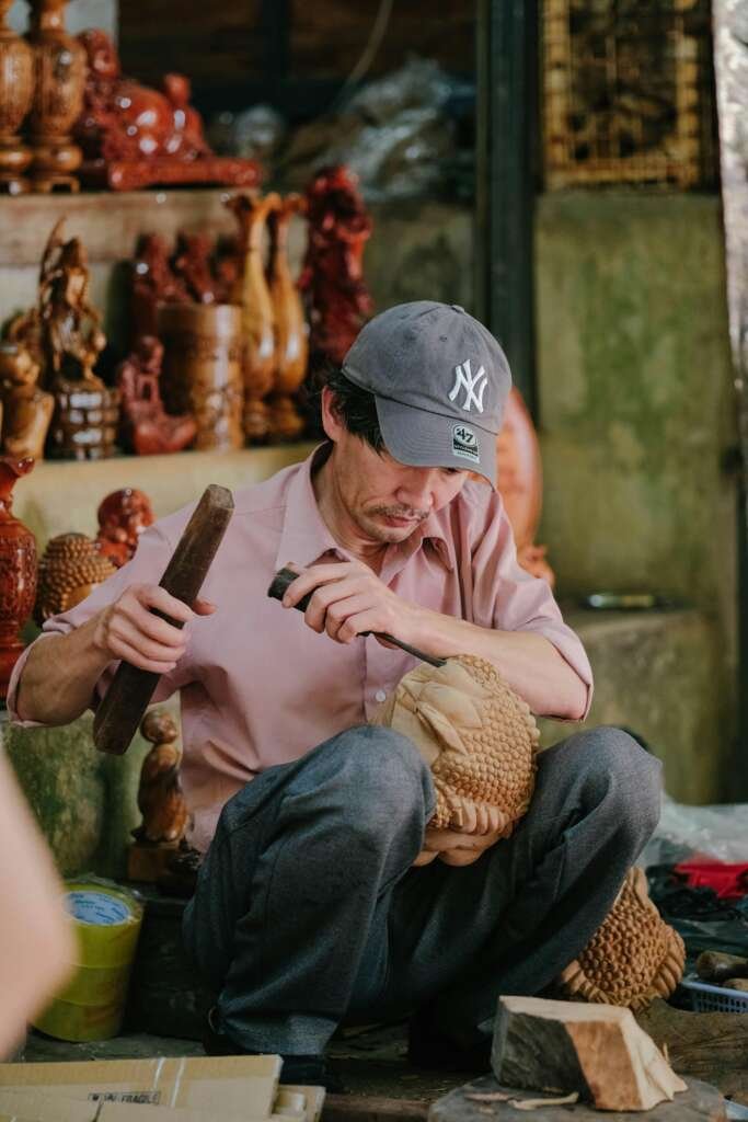Captured moment of skilled artisan carving detailed wooden sculptures in a workshop.