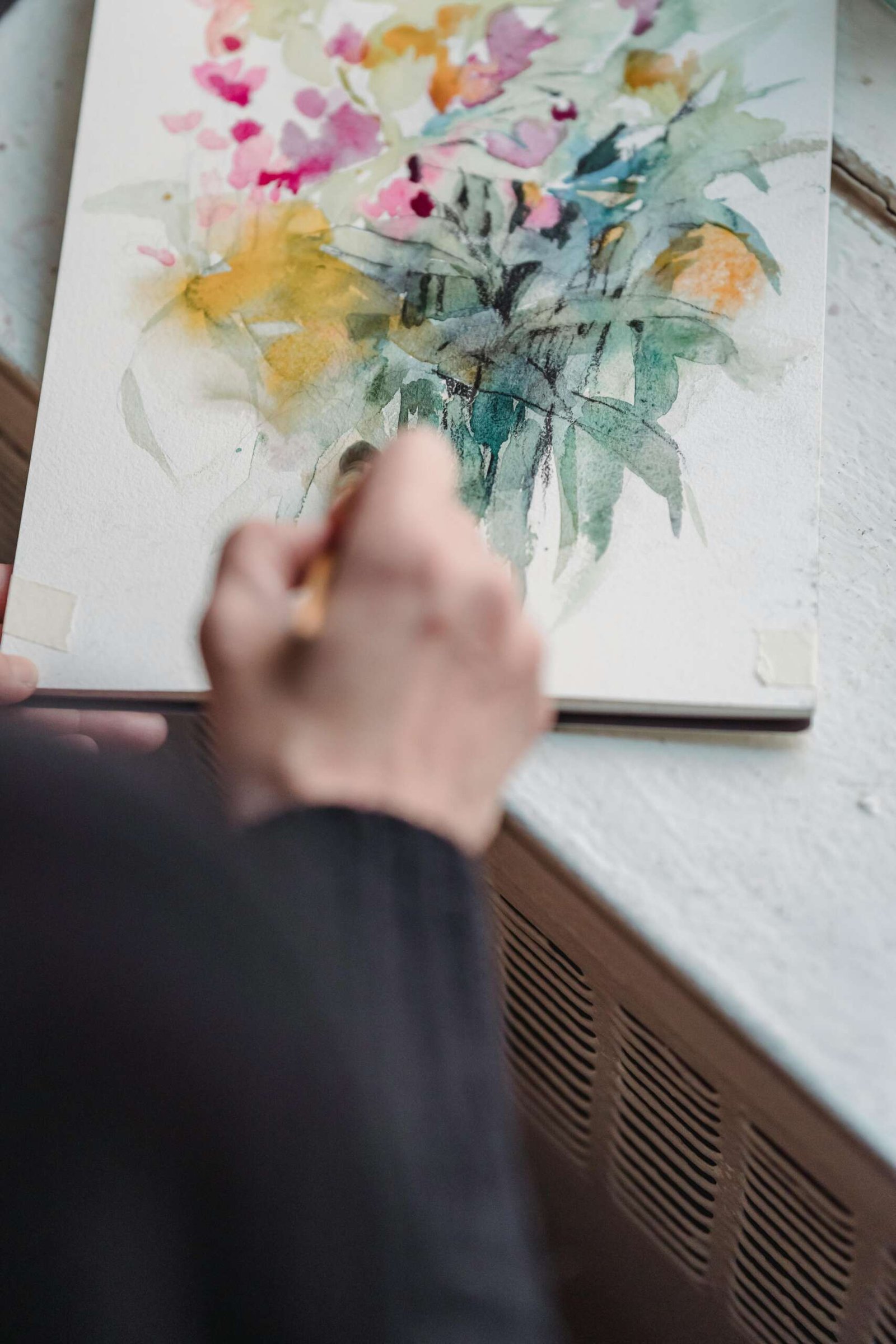 An artist paints a colorful floral watercolor on canvas, showcasing creativity and imagination.