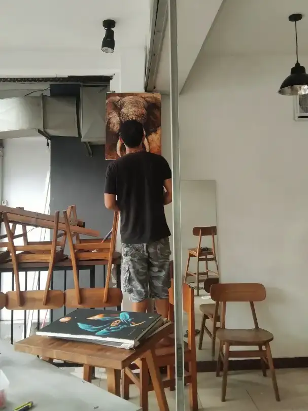 artist hanging elephant painting inside Arts of Bali gallery under construction