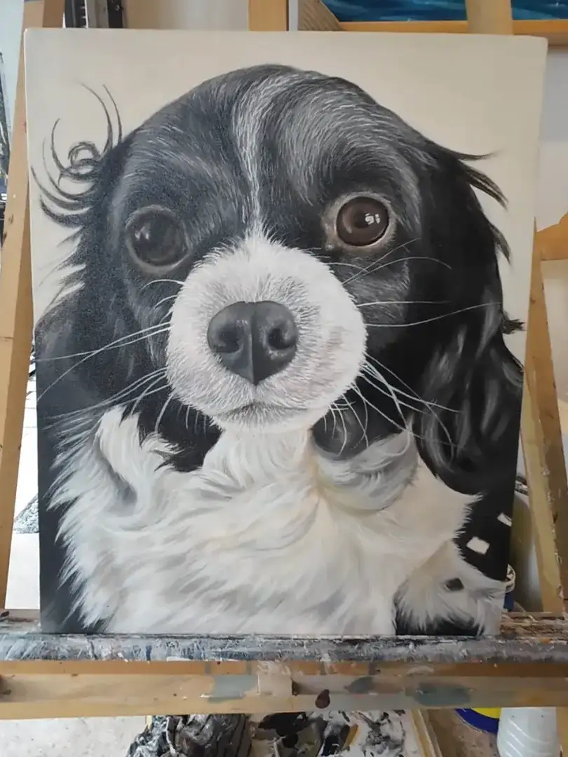 A finished masterful animal realism painting of a black and white dog on display at Arts of Bali gallery.