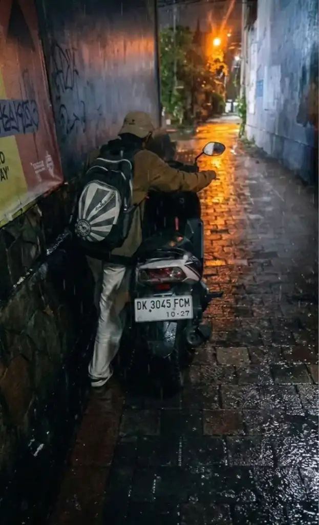Commissioned Textured Realism Paintings in Bali - Arts of Bali Pushing a motorcycle through a rainy Bali street after completing a successful art delivery.