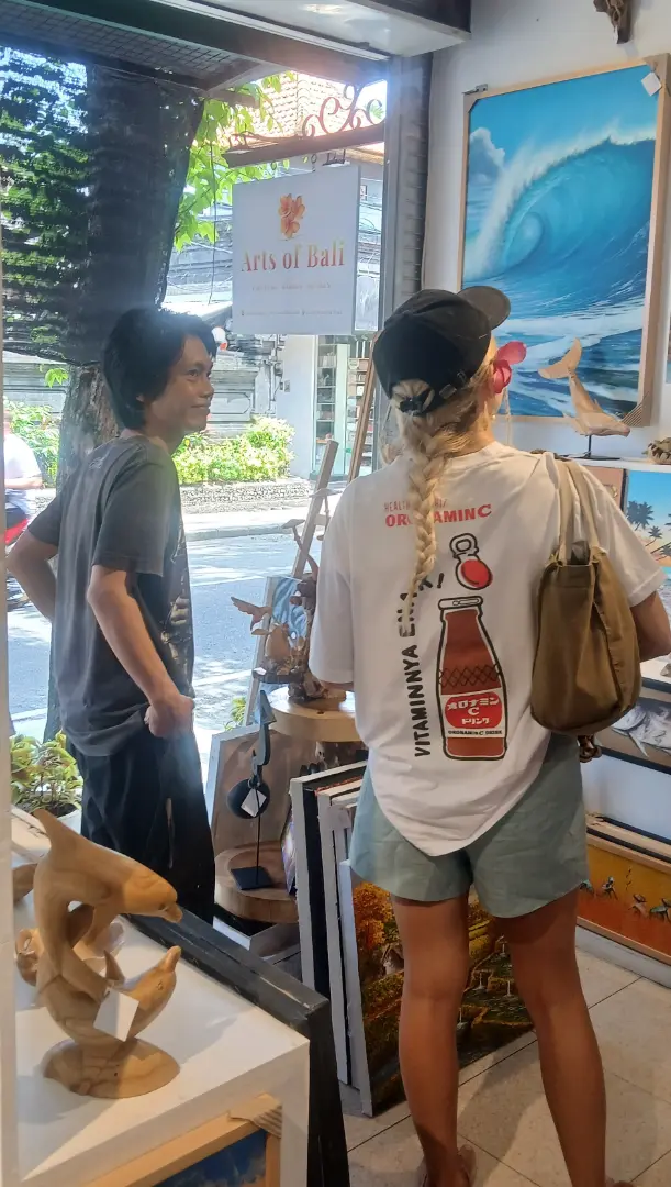 Visitor at Arts of Bali gallery — Jalan Raya Seminyak A tourist browsing original paintings and wood sculptures at Arts of Bali fine art gallery Seminyak Bali