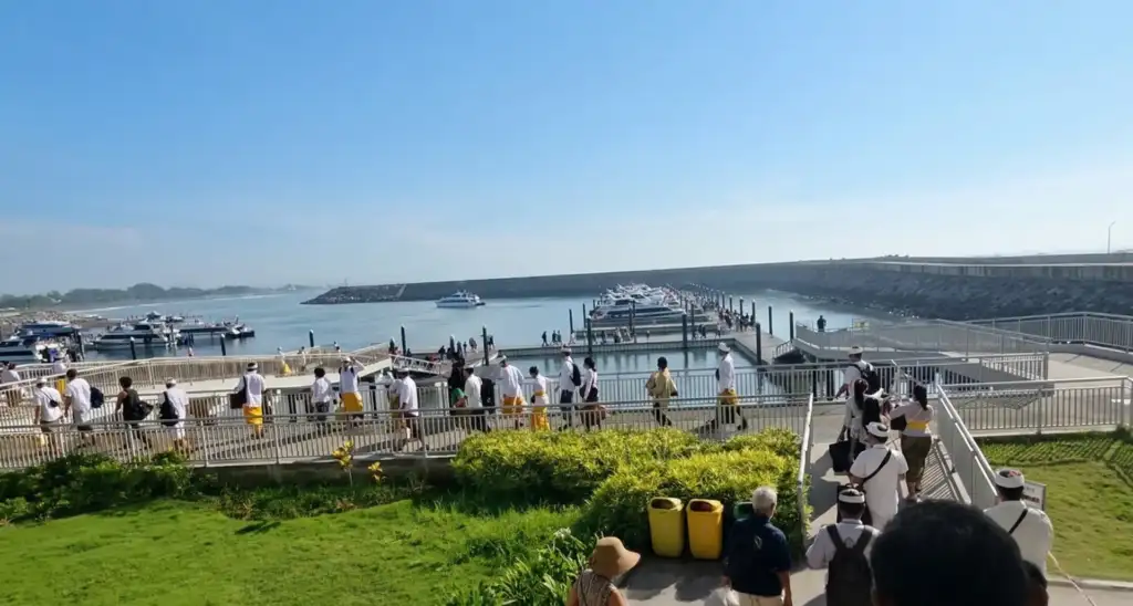 From the Noise to the Silence: Nyepi with the Arts of Bali Family - Arts of Bali Balinese people dressed in white traditional attire walking along a harbor pier heading to boats before Nyepi celebrations