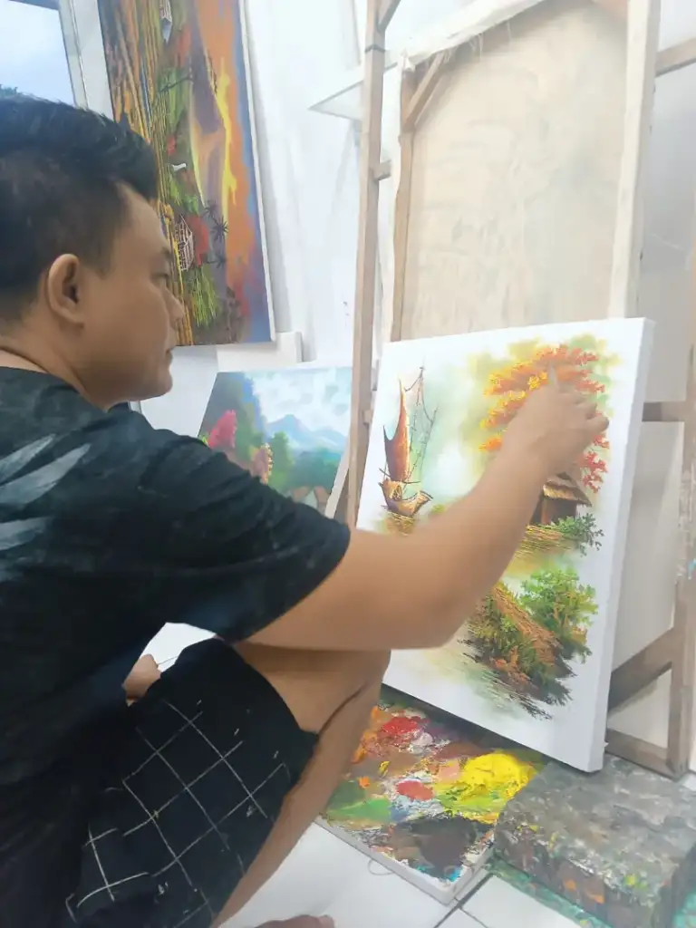 A.Gandara: The Man Who Found Himself in the Texture of the Land - Arts of Bali Balinese artist A. Gandara painting traditional sailboat landscape in Arts of Bali studio Seminyak