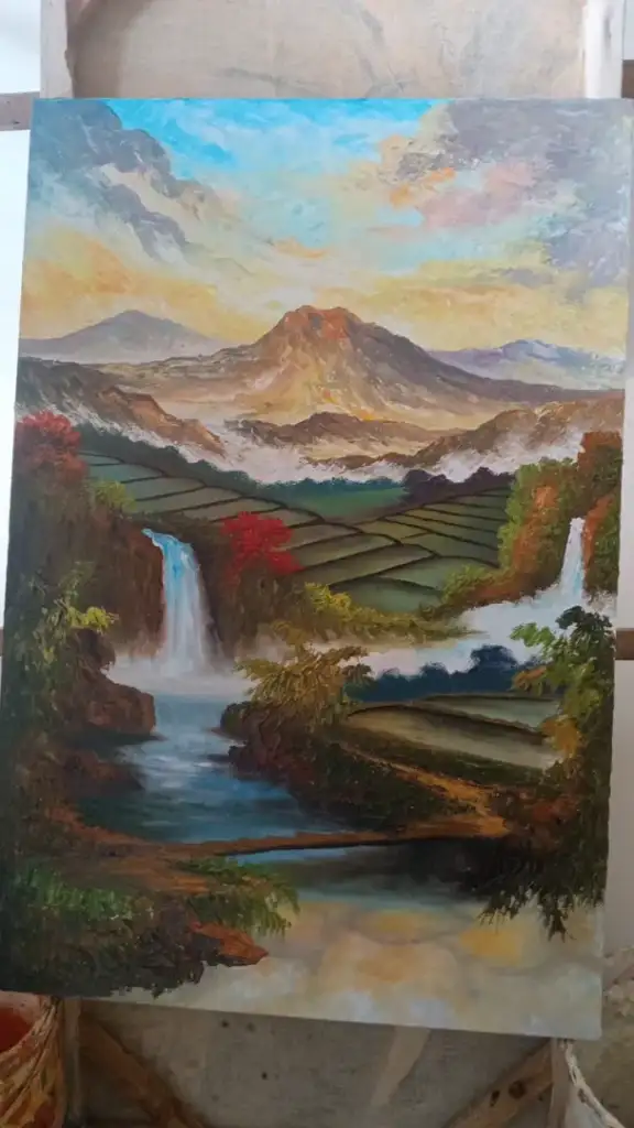 A.Gandara: The Man Who Found Himself in the Texture of the Land - Arts of Bali A. Gandara applying paint to volcano and waterfall landscape canvas in studio