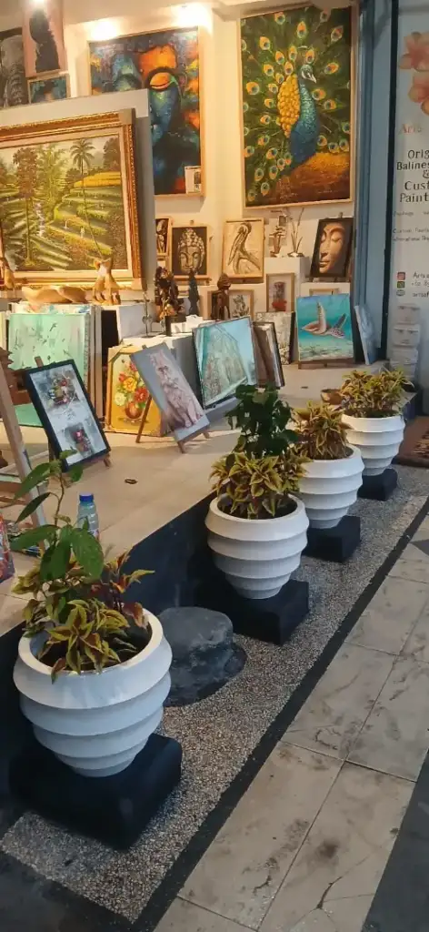 Outdoor display setup of Arts of Bali gallery on Seminyak main street with white pots and paintings - Arts of Bali