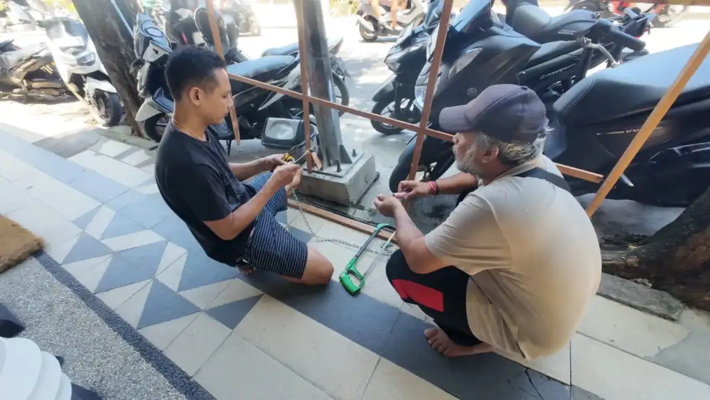 Team preparing chain links and hardware for welcome sign outside Arts of Bali gallery Seminyak