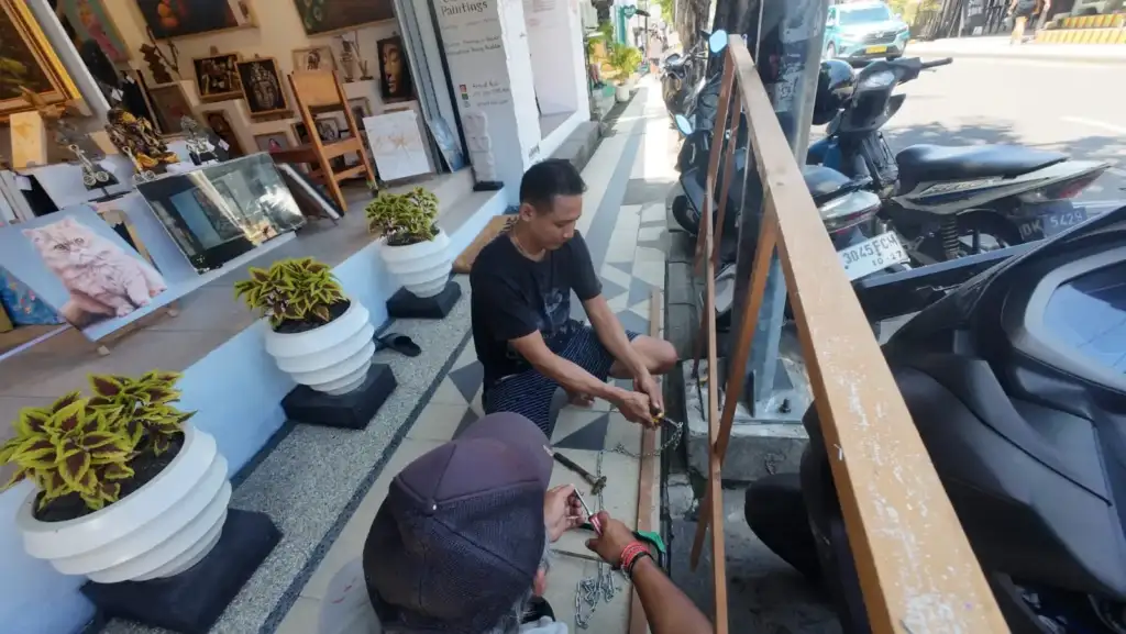 Team attaching chain links and screws for welcome sign installation at Arts of Bali Balinese art gallery