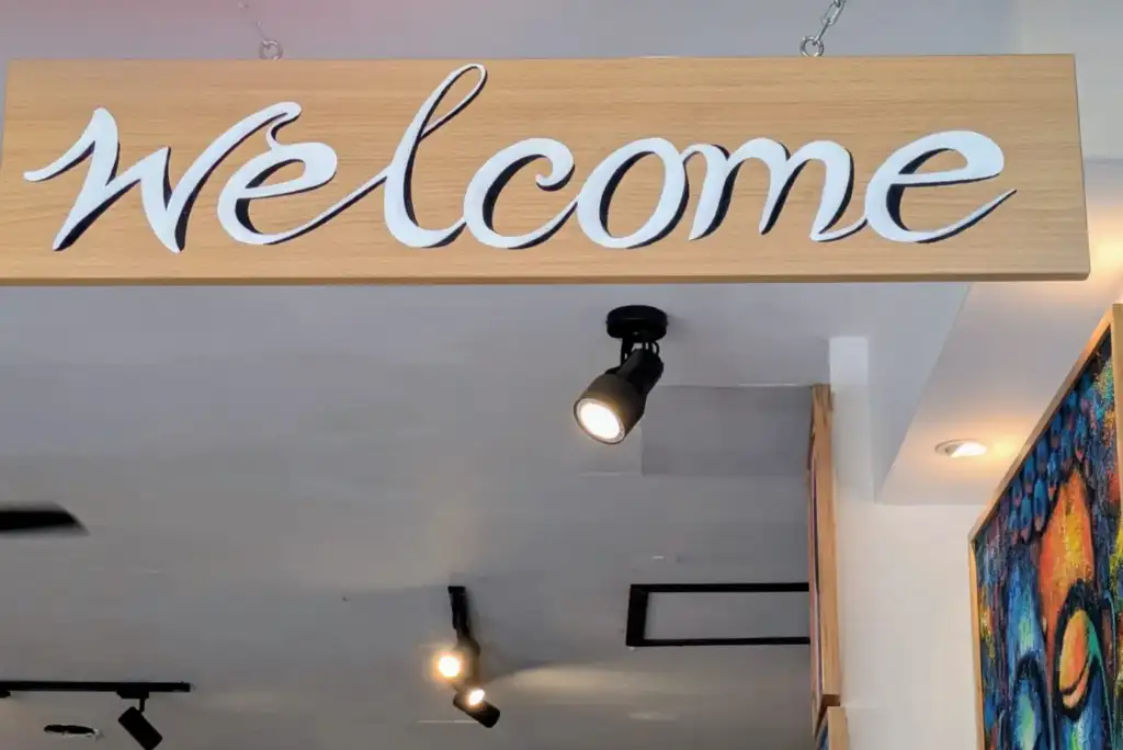 Close-up of hand-painted welcome sign with white cursive lettering at Arts of Bali gallery Seminyak