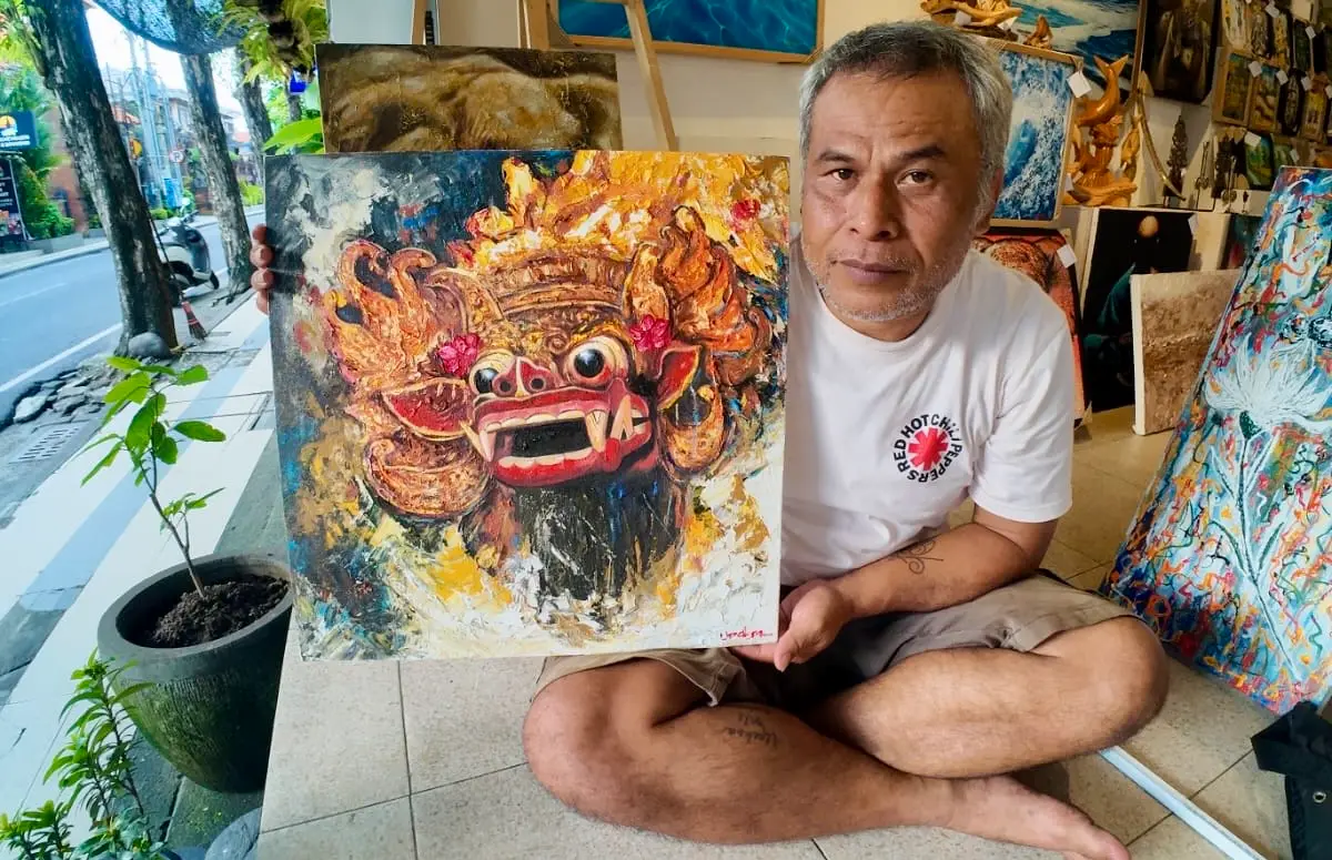 Upeksa — Palette Knife Artist at Arts of Bali, Holding Barong Painting, Seminyak Bali palette knife artist Upeksa sitting outside Arts of Bali gallery on Jalan Raya Seminyak holding an original Barong impasto oil painting