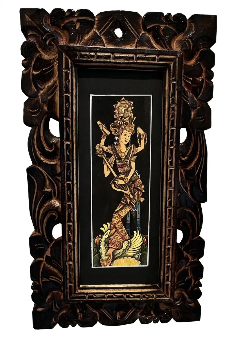 Balinese mythology painting — Balinese Dewi goddess figure in full ceremonial costume standing on mythological creature, black background, ornate hand-carved dark wooden frame