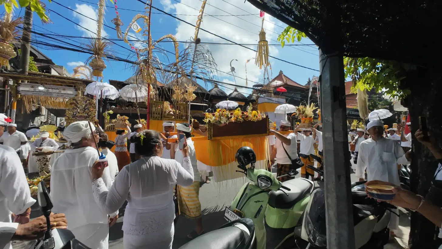 Balinese worshippers carrying elaborately decorated golden jempana sacred palanquins with white tedung umbrellas held above them during an Odalan ceremony procession in Seminyak Bali