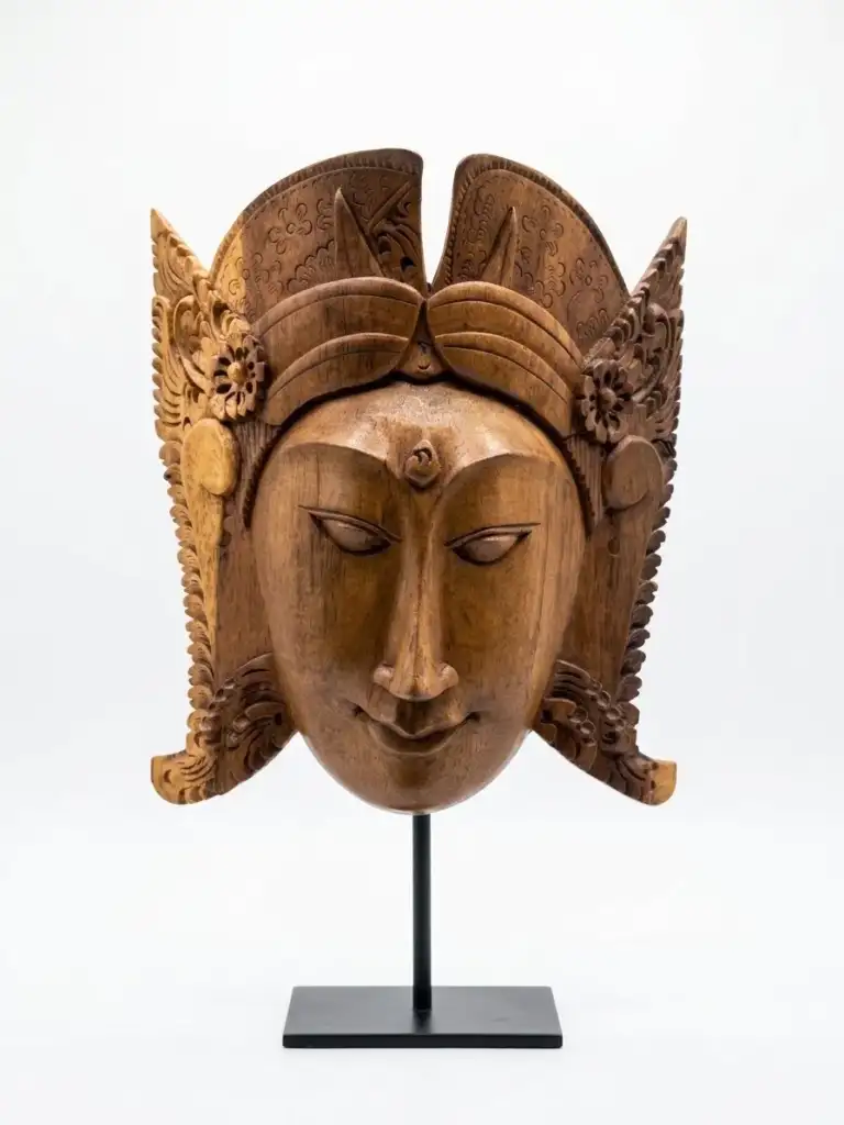 Balinese wood carving mask — serene deity face with ornate wing and crown, hand-carved in local hardwood, Arts of Bali gallery