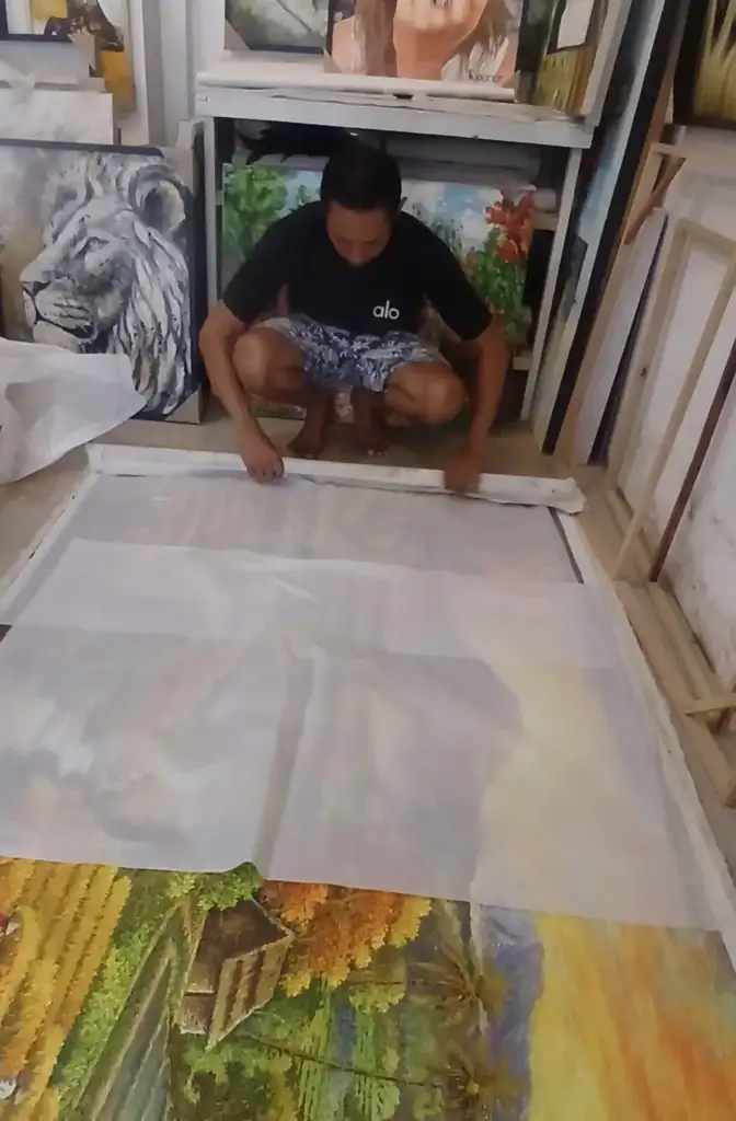 How to Ship Art from Bali: Packing, Costs, and Customs - Arts of Bali Arts of Bali gallery staff carefully rolling a large original painting for international shipping, Seminyak gallery