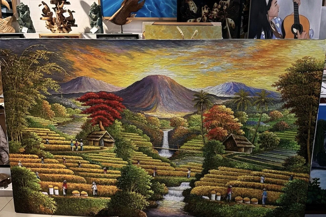 Close-up view of a textured oil painting showing a volcano with thick impasto sky in orange and purple tones, rice terraces, red flame trees, and a small waterfall, Arts of Bali gallery display