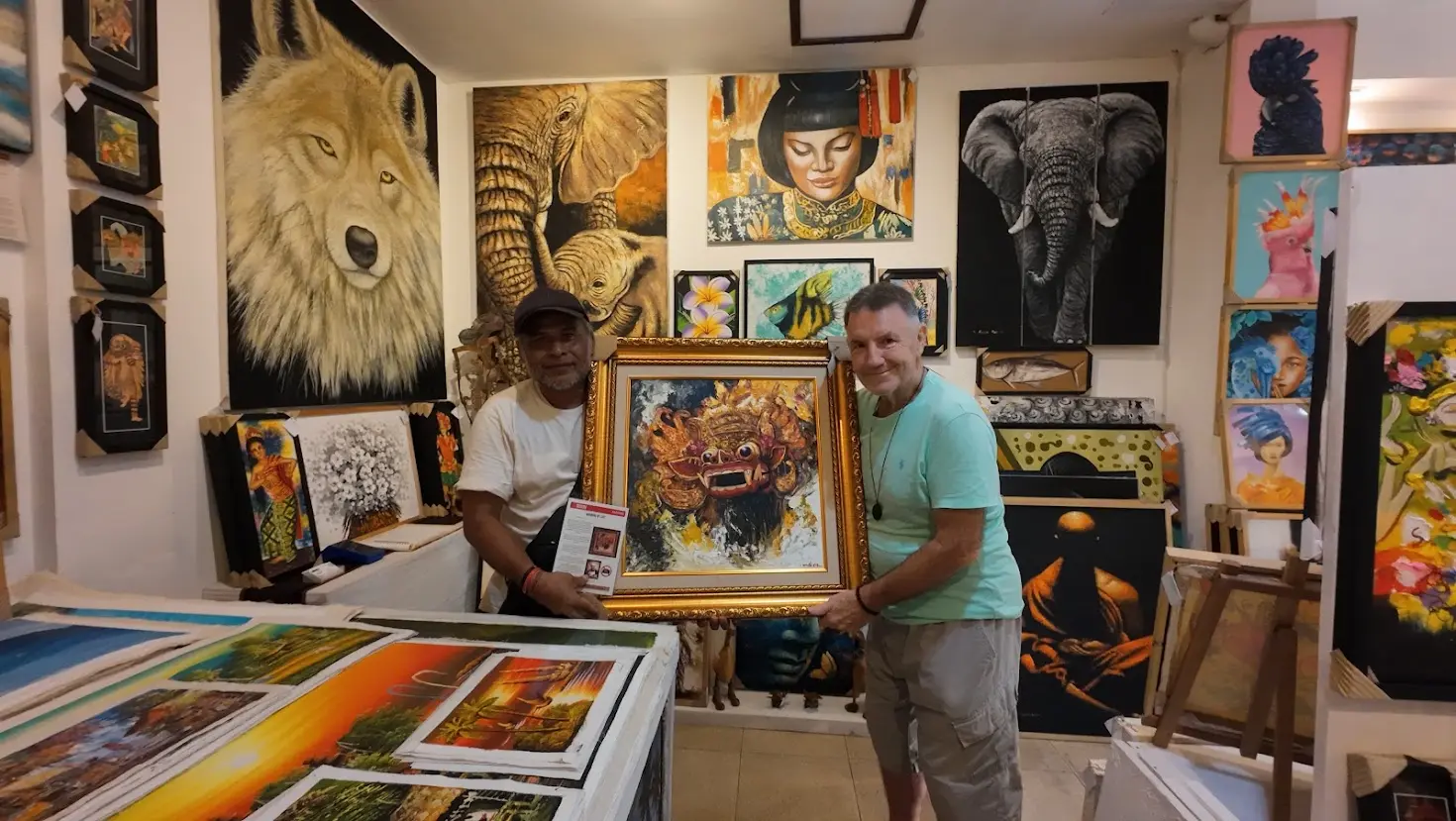Gallery staff and customer with a framed Barong mask painting, Arts of Bali gallery, Seminyak