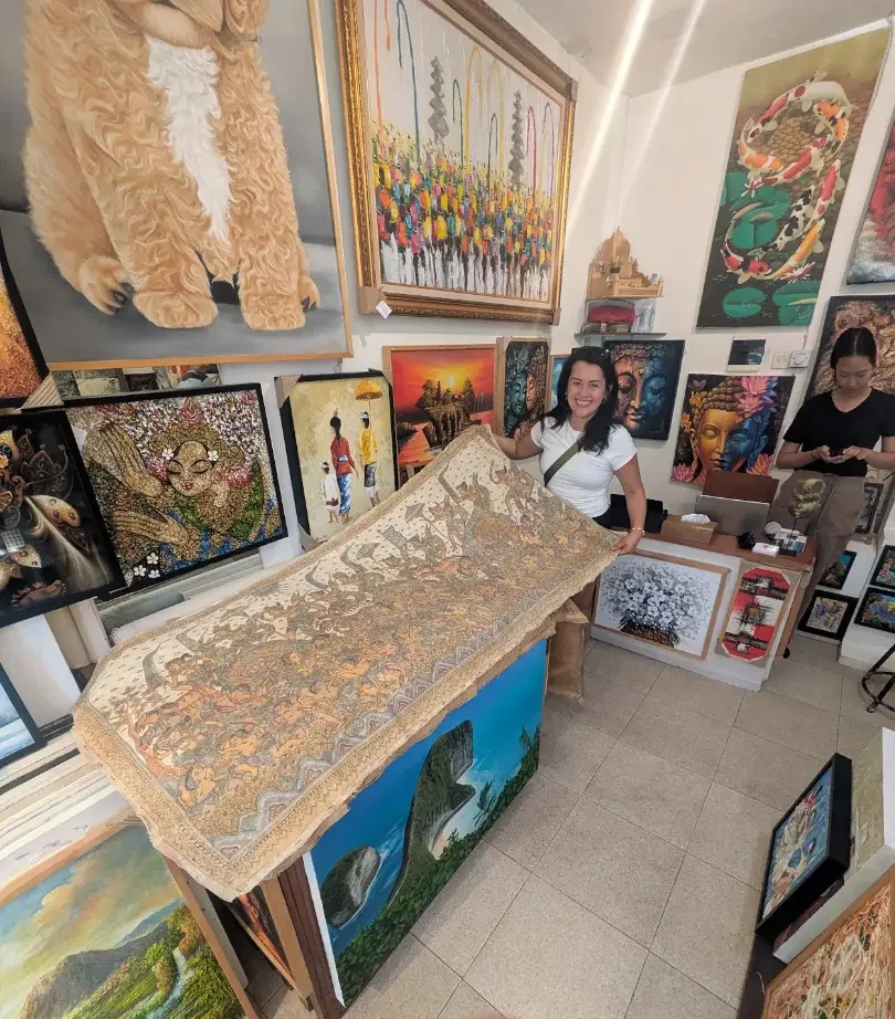 Customer holding a Kamasan-style scroll painting at Arts of Bali gallery, Seminyak