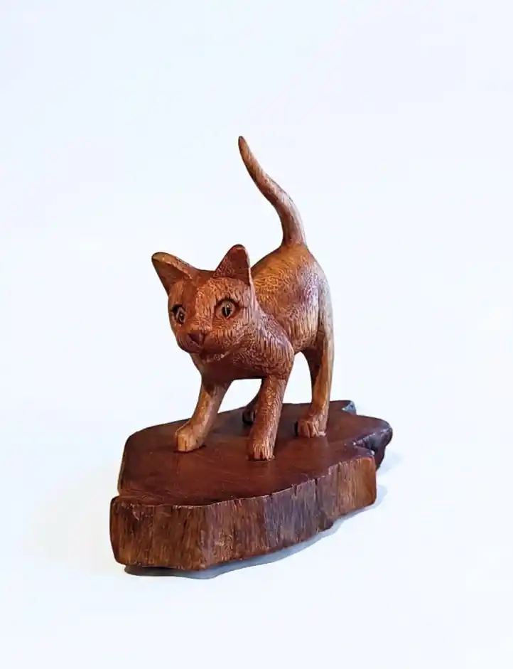 Hand-carved standing wooden cat statue with raised tail on natural wood plinth from Arts of Bali.