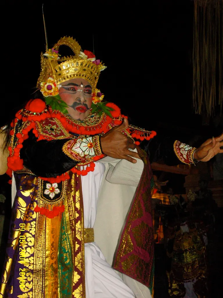Costumed Gambuh dancer in a gold headdress photographed at Batuan, Bali, against a dark background
