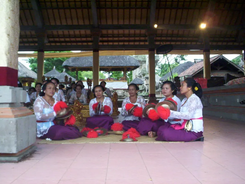 Women in white tops and purple sarongs holding ceng ceng cymbals in a Balinese gamelan in Ubud